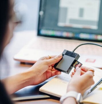 Praktyczny przewodnik po chmurze: jak bezpiecznie przechowywać dane w Google Drive, OneDrive i innych usługach dla użytkownika domowego Osoba wkłada kartę SD do czytnika obok laptopa na biurku