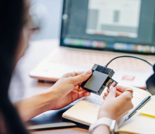 Praktyczny przewodnik po chmurze: jak bezpiecznie przechowywać dane w Google Drive, OneDrive i innych usługach dla użytkownika domowego Osoba wkłada kartę SD do czytnika obok laptopa na biurku